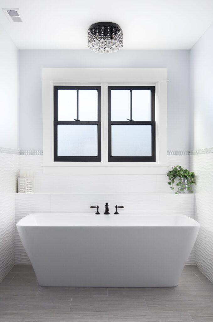 Freestanding tub under a window with white tile, AJH Construction bathroom remodel