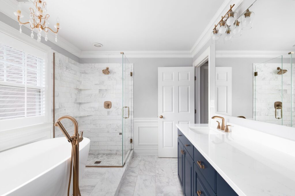 Marble tile walk-in shower with frameless glass and navy vanity, AJH Construction bathroom remodel, San Jose